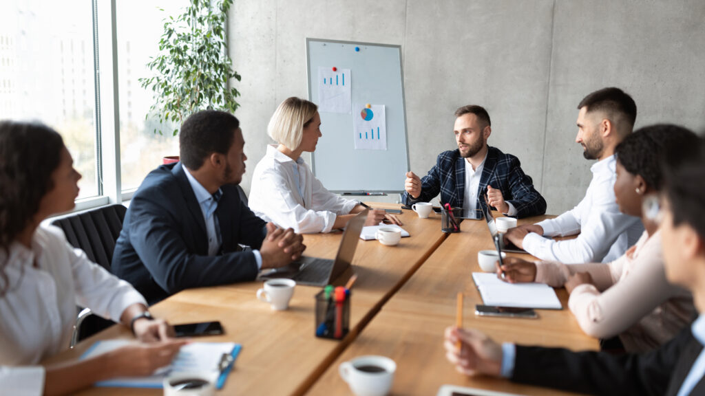 Multiracial Colleagues At Corporate Meeting Sitting At Desk